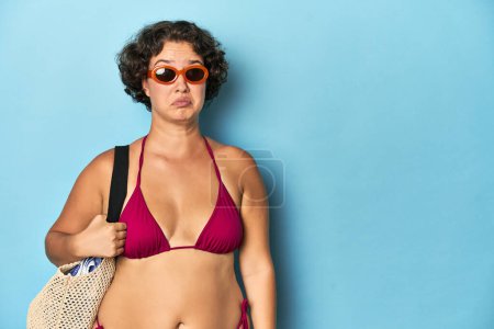 Photo for Young woman in bikini with beach bag confused, feels doubtful and unsure. - Royalty Free Image