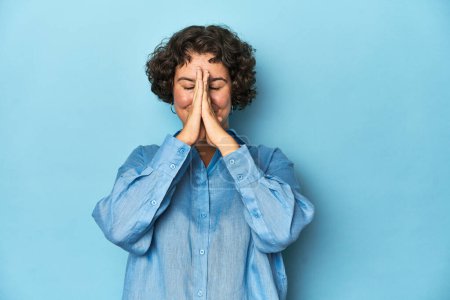 Photo for Young Caucasian woman with short hair holding hands in pray near mouth, feels confident. - Royalty Free Image