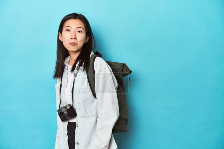 Foto de Joven viajero asiático listo para capturar aventuras, se encoge de hombros y los ojos abiertos confundido. - Imagen libre de derechos