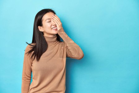 Photo for Young Asian woman in brown turtleneck, laughing happy, carefree, natural emotion. - Royalty Free Image