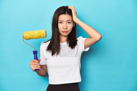Photo for Young Asian woman with paint roller, DIY concept, being shocked, she has remembered important meeting. - Royalty Free Image