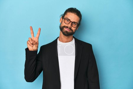 Photo for Businessman in suit with eyeglasses and beard joyful and carefree showing a peace symbol with fingers. - Royalty Free Image