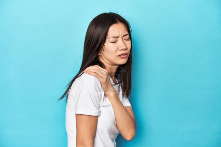 Téléchargez les photos : Jeune femme asiatique en t-shirt blanc, plan studio, ayant une douleur à l'épaule. - en image libre de droit