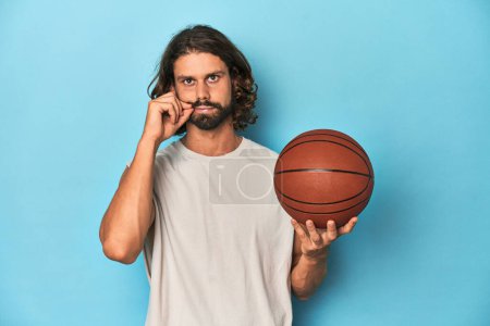 Photo for Bearded man with basketball in blue studio with fingers on lips keeping a secret. - Royalty Free Image