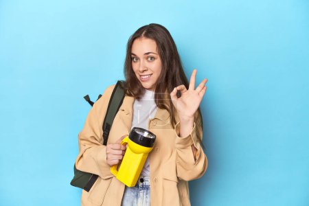 Photo for Adventurous woman with flashlight and backpack ready to explore cheerful and confident showing ok gesture. - Royalty Free Image