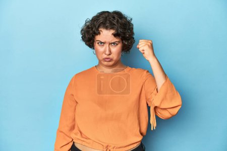Foto de Mujer joven caucásica con pelo corto mostrando puño a cámara, expresión facial agresiva. - Imagen libre de derechos