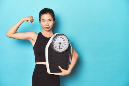 Photo for Asian sportswoman holding scale, showing strength - Royalty Free Image