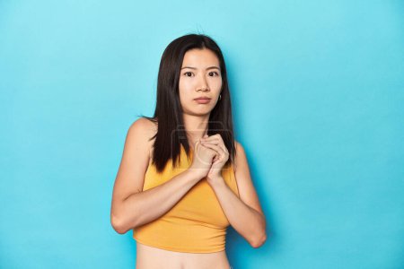 Photo for Asian woman in summer yellow top, studio setup, scared and afraid. - Royalty Free Image