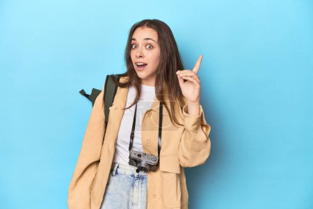 Téléchargez les photos : Jeune voyageuse caucasienne avec caméra et sac à dos ayant une idée, concept d'inspiration. - en image libre de droit