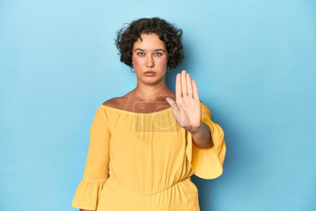 Photo for Young Caucasian woman with short hair standing with outstretched hand showing stop sign, preventing you. - Royalty Free Image