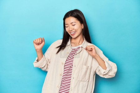 Photo for Asian woman in layered shirt and striped t-shirt, dancing and having fun. - Royalty Free Image