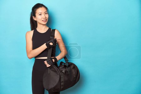 Photo for Asian sportswoman holding gym backpack, studio shot. - Royalty Free Image