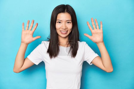 Téléchargez les photos : Jeune femme asiatique en t-shirt blanc, plan studio, montrant le numéro dix avec les mains. - en image libre de droit