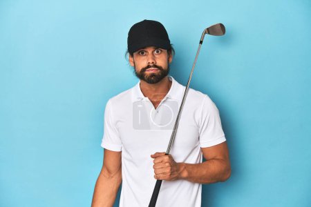 Photo for Long-haired golfer with club and hat shrugs shoulders and open eyes confused. - Royalty Free Image