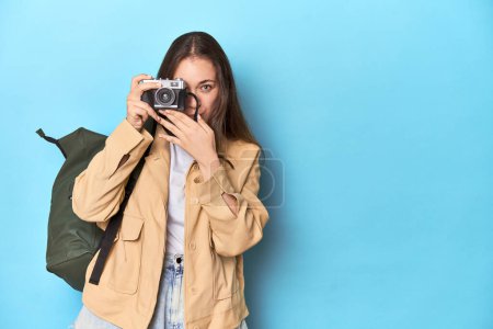 Foto de Mujer viajera tomando fotos con una cámara vintage en azul. - Imagen libre de derechos