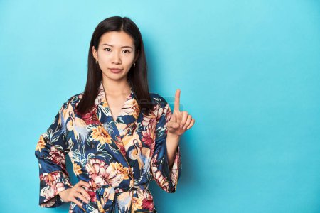 Foto de Elegante joven asiática en kimono, toma de estudio mostrando el número uno con el dedo. - Imagen libre de derechos