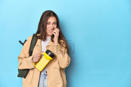 Photo for Adventurous woman with flashlight and backpack ready to explore biting fingernails, nervous and very anxious. - Royalty Free Image
