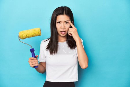 Photo for Young Asian woman with paint roller, DIY concept, showing a disappointment gesture with forefinger. - Royalty Free Image