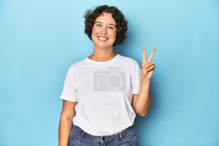 Téléchargez les photos : Jeune femme caucasienne aux cheveux courts joyeuse et insouciante montrant un symbole de paix avec les doigts. - en image libre de droit