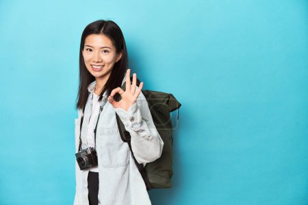 Photo for Young Asian traveler ready to capture adventures, cheerful and confident showing ok gesture. - Royalty Free Image
