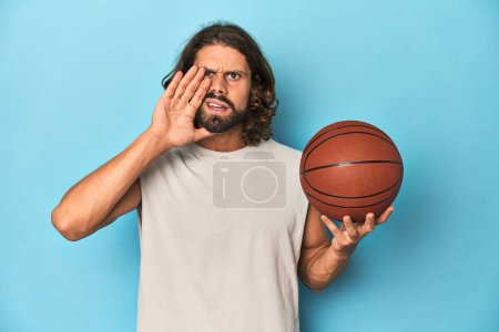 Photo for Bearded man with basketball in blue studio shouting and holding palm near opened mouth. - Royalty Free Image