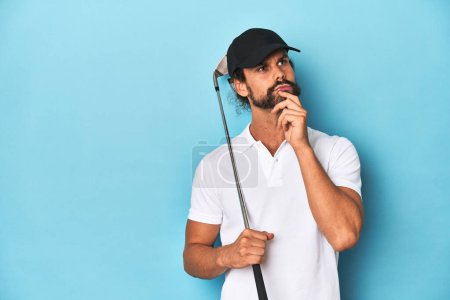 Foto de Golfista de pelo largo con club y sombrero mirando hacia los lados con expresión dudosa y escéptica. - Imagen libre de derechos