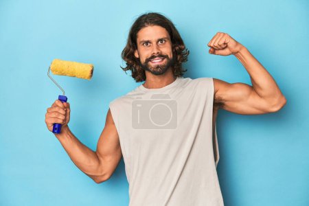 Photo for Bearded man painting with a yellow roller raising fist after a victory, winner concept. - Royalty Free Image
