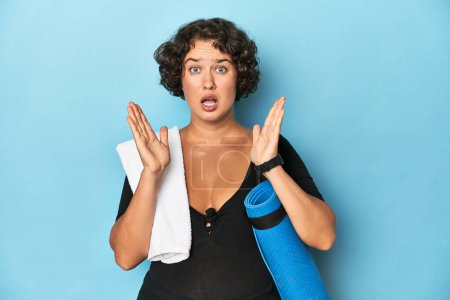Téléchargez les photos : Athlétique jeune femme avec tapis de yoga surpris et choqué. - en image libre de droit