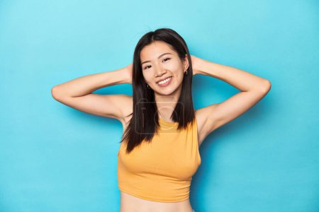 Téléchargez les photos : Femme asiatique en haut jaune d'été, installation studio, bras tendus, position détendue. - en image libre de droit