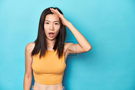 Photo for Asian woman in summer yellow top, studio setup, shouts loud, keeps eyes opened and hands tense. - Royalty Free Image