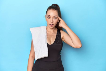 Photo for Fit young woman with a towel on her shoulder, studio shot showing a disappointment gesture with forefinger. - Royalty Free Image
