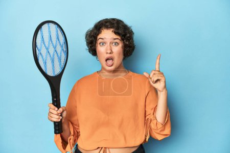 Téléchargez les photos : Jeune femme avec raquette de moustique électrique Jeune femme avec raquette de moustique électrique une idée, concept d'inspiration. - en image libre de droit