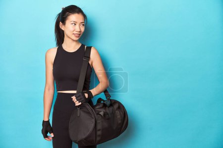 Photo for Asian sportswoman holding gym backpack, studio shot. - Royalty Free Image