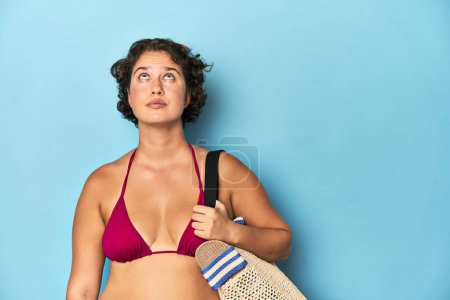 Foto de Joven mujer caucásica en bikini sosteniendo una bolsa de playa, disparo de estudio. - Imagen libre de derechos