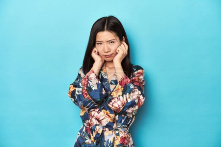 Foto de Elegante joven asiática en kimono, estudio de tiro cubriendo las orejas con las manos. - Imagen libre de derechos