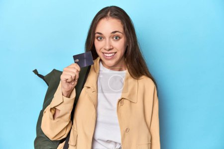 Téléchargez les photos : Jeune voyageur femme avec sac à dos et carte de crédit sur bleu. - en image libre de droit