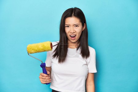 Téléchargez les photos : Jeune femme asiatique avec rouleau de peinture, concept de bricolage, criant très en colère et agressif. - en image libre de droit