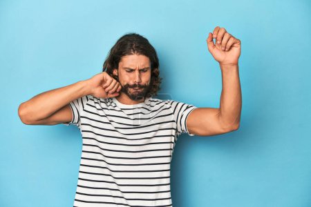 Photo for Bearded man in a striped shirt, blue backdrop dancing and having fun. - Royalty Free Image