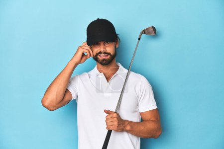 Téléchargez les photos : Golfeur aux cheveux longs avec club et chapeau couvrant les oreilles avec les mains. - en image libre de droit