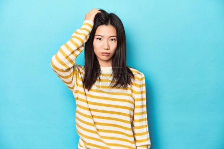 Photo for Asian woman in striped yellow sweater, tired and very sleepy keeping hand on head. - Royalty Free Image