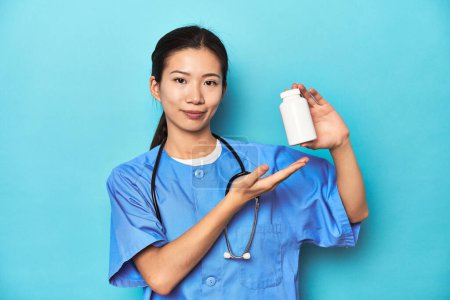Photo for Asian nurse with a pill bottle, studio shot. - Royalty Free Image