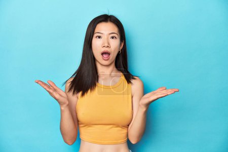 Photo for Asian woman in summer yellow top, studio setup, surprised and shocked. - Royalty Free Image