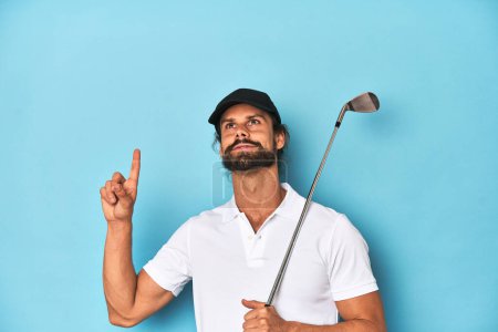 Foto de Golfista de pelo largo con palo y sombrero apuntando al revés con la boca abierta. - Imagen libre de derechos