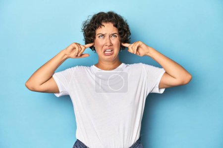 Photo for Young Caucasian woman with short hair covering ears with fingers, stressed and desperate by a loudly ambient. - Royalty Free Image