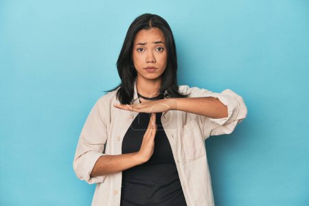 Photo for Filipina young woman on blue studio showing a timeout gesture. - Royalty Free Image