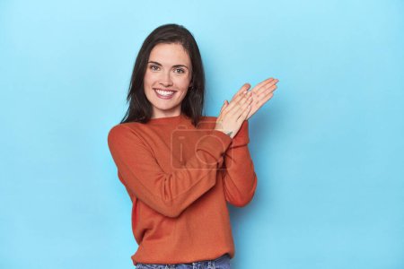Photo for Young caucasian woman on blue backdrop feeling energetic and comfortable, rubbing hands confident. - Royalty Free Image