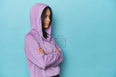 Téléchargez les photos : Filipina en sweat à capuche violet sur fond de studio bleu - en image libre de droit