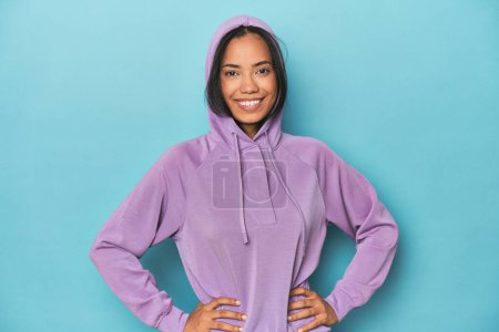 Photo for Filipina in purple sportswear hoodie on a blue studio background - Royalty Free Image