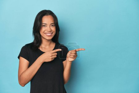 Photo for Filipina young woman on blue studio excited pointing with forefingers away. - Royalty Free Image