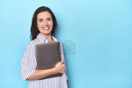 Téléchargez les photos : Femme d'affaires avec ordinateur portable sur fond bleu - en image libre de droit